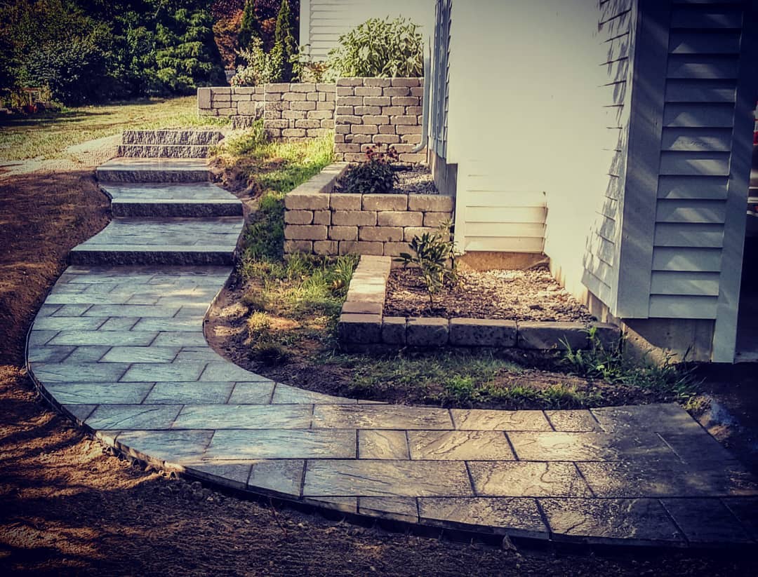 Windham Ridge Pavers paired with Woodbury Granite steps compliment the house and the existing garden walls. The walkway winds as it climbs the grade but the paver pattern remains square to the house. The details are key to a quality finished product.